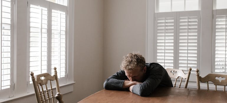 A stressed man sitting in the dining room.