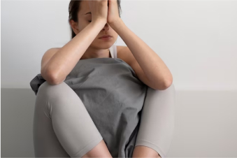 a worried woman sitting on the floor with hands over her face