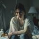 woman struggling with meth addiction sits on a bed, looking distressed